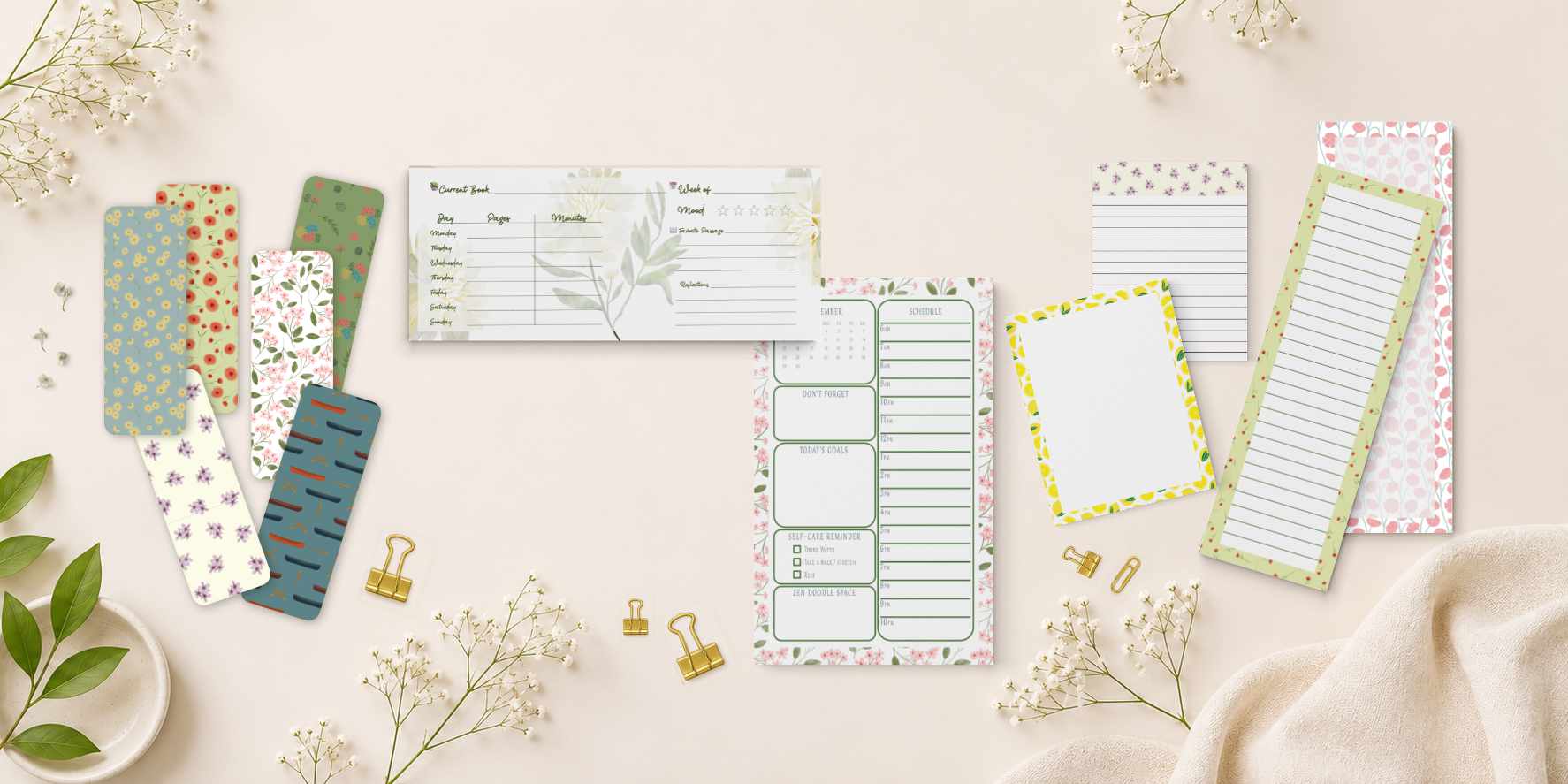 Overhead view of handmade botanical bookmarks, a weekly planner pad, sticker sheets, a fountain pen and eucalyptus sprigs on a blush paper background